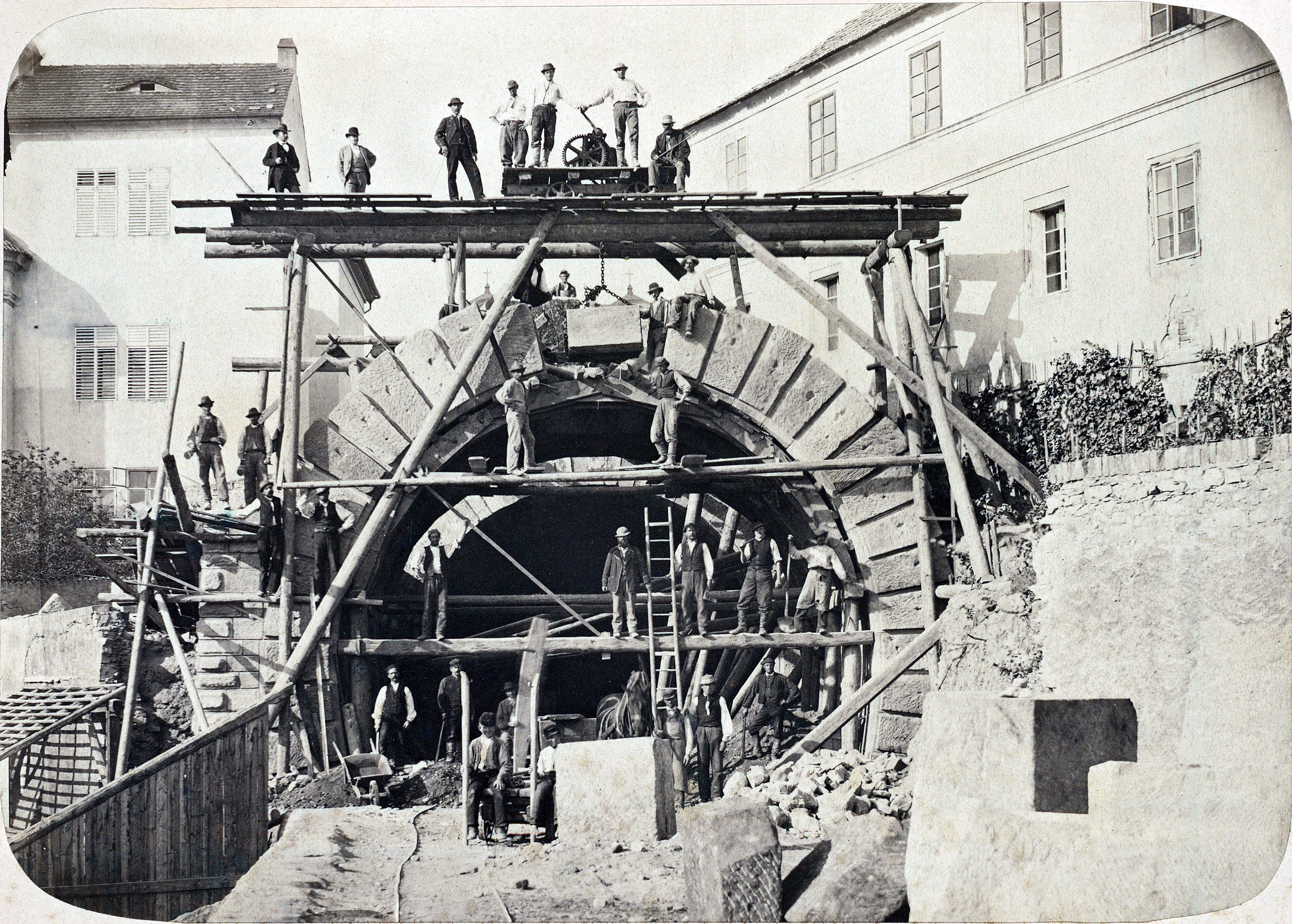 Historische Fotografie eines Teams beim Bau eines Steinbogens auf einem Gerüst
